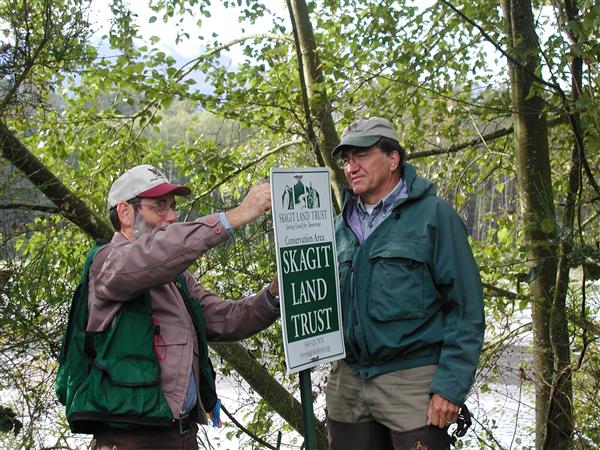 Skagit Land Trust Land Steward Dick Raisler installs a property sign. Photograph credit: Skagit Land Trust staff.